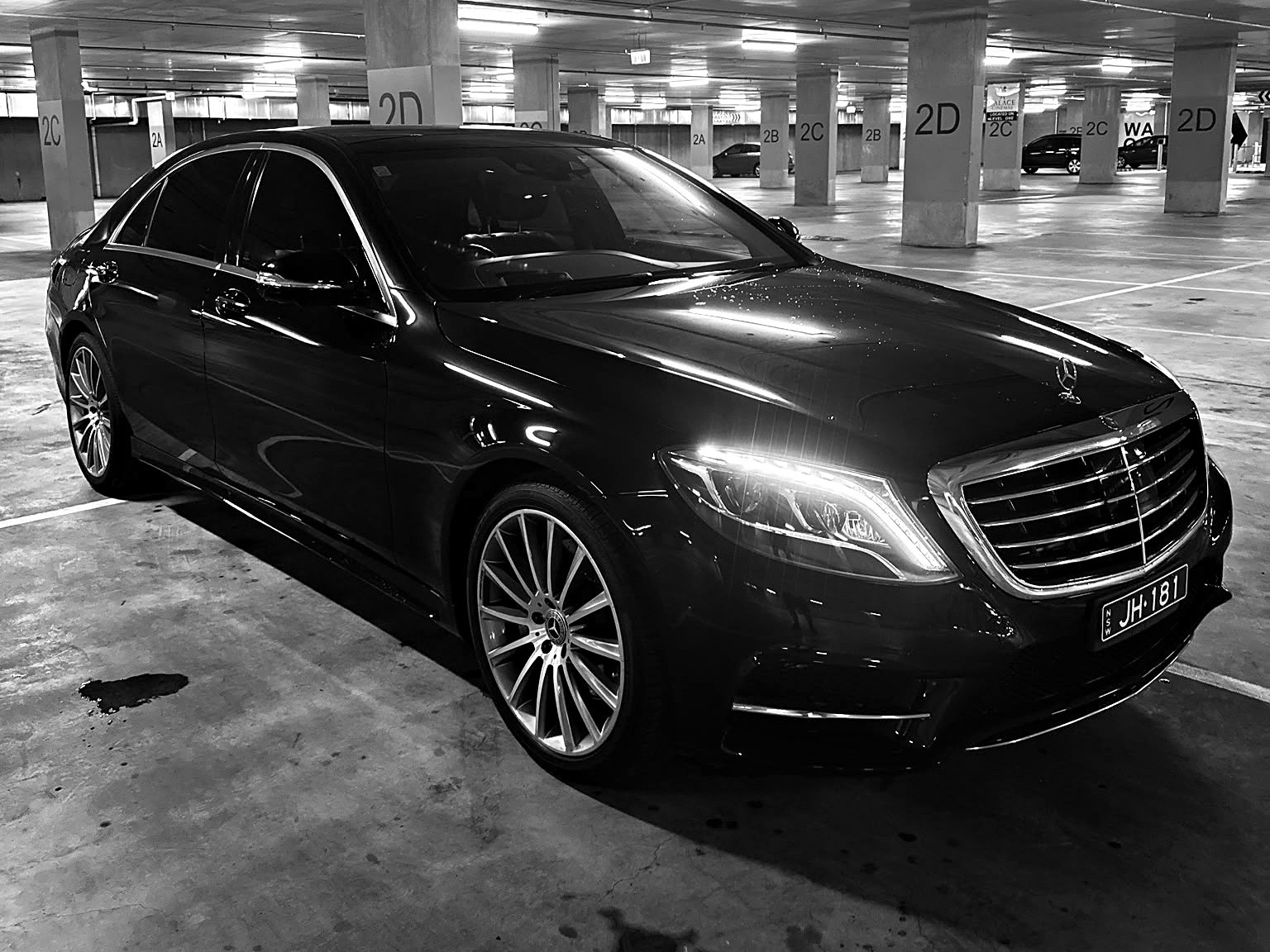 Black-and-white photograph of the black Mercedes S-Class AMG Line long-wheelbase sedan, shown from the front three-quarter angle.